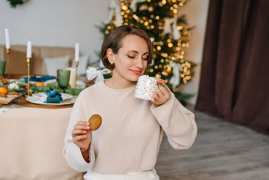 Happy woman enjoying cookie hot cocoa Christmas table