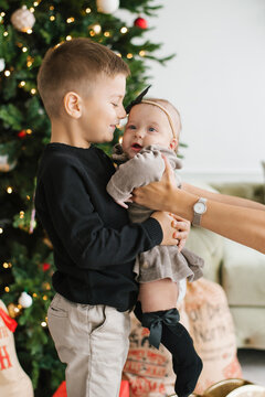 Brother Holding Baby Sister By Christmas Tree