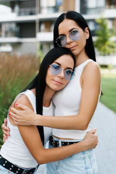 Twin Sisters Embracing near Modern City Building