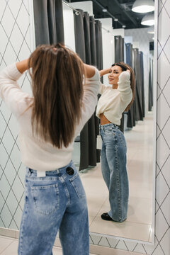 Young Woman Trying On Denim Jeans In Store Mirror