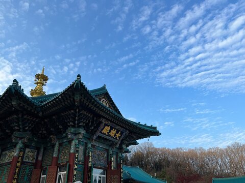 파란 하늘과 구름 아래 고즈넉하게 서 있는 한국 전통 사찰 대웅전
