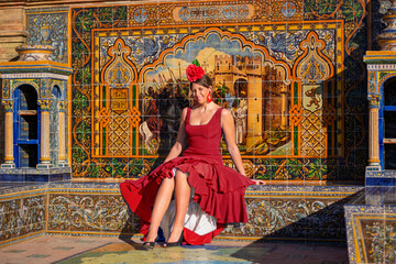 a beautiful girl in a flamenco dress sitting in front of the sun's rays © corradobarattaphotos