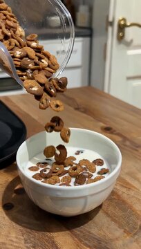 Gourmet 4K breakfast commercial footage shot at an extreme 1000fps tracking multi-colored cereal loops dropping gracefully into a bowl of fresh milk causing miniature liquid crowns and splashes