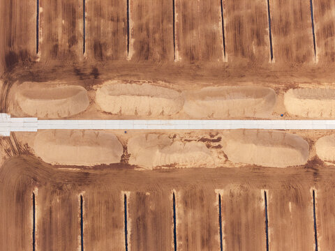 Aerial view of industrial peat extraction site with parallel drainage trenches and mounds of harvested peat in Latvia.