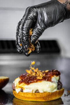 Chef adding fried onions to gourmet angus beef burger