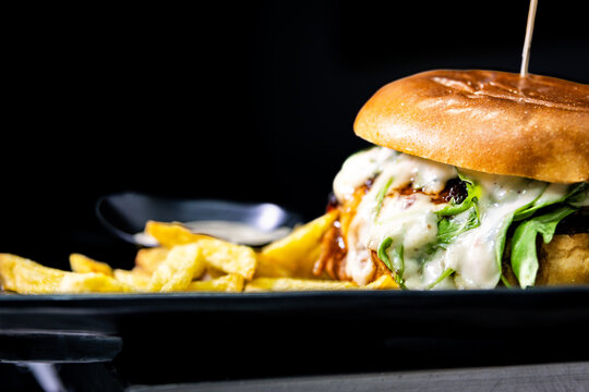 Gourmet angus beef burger with melting cheddar, bacon, arugula and crispy fries