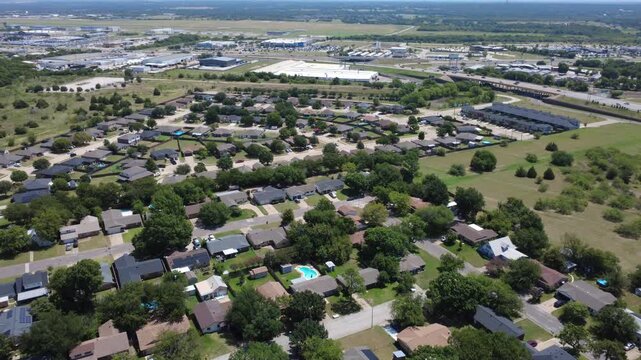 Curving roadways link residential enclaves near Interstate 35W across Dallas Fort Worth metroplex. Single family homes, modern townhomes, retention ponds dot landscape, Burleson, Texas