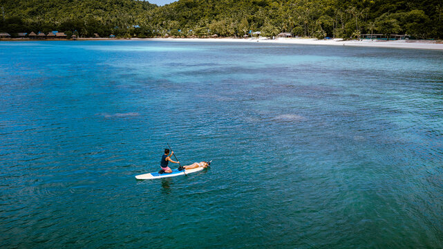 Top aerial view of Group of tourist are enjoy on water sport paddle sup-board  along at the sea under crystal clear of water in the island of summer trip
