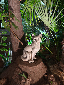 Estatua de piedra de un gato en un jard&iacute;n de noche