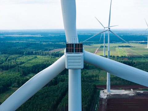 Aerial view of wind turbines in Kaigu Bog featuring advanced bird protection technology with cameras and sensors set against a vast forest landscape in Latvia.