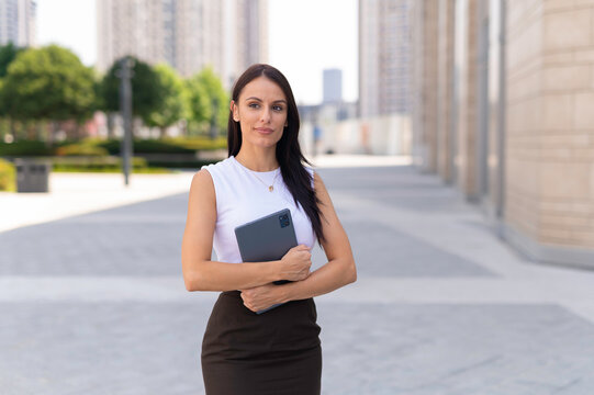 Confident businesswoman holding tablet standing in urban environment