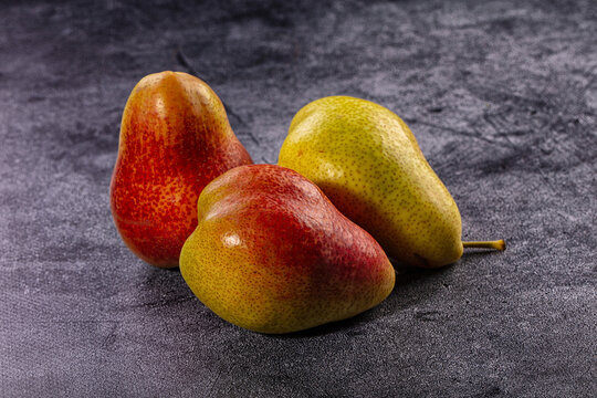 Three ripe pears on dark stone surface