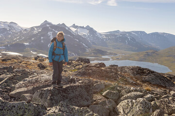 Obraz premium Beautiful european family with children and pet dog, hiking Kyrkja mountain on a beautiful sunny summer day, sunset, snow, lakes, valley