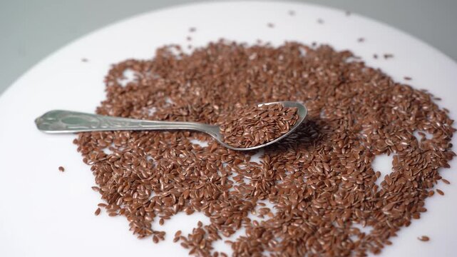 Healthy Flax Seeds (Linum usitatissimum) on a White Background with a Spoon, Rich in Omega-3 Fatty Acids