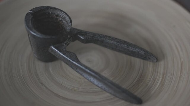Metal nutcracker tool with cracked walnuts on a clean background