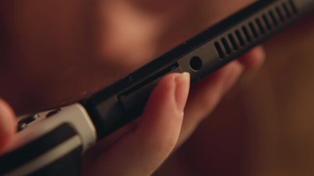Tight handheld close view of electric shaver guided along facial skin, fingers holding matte plastic handle while metal blade housing makes light contact with visible stubble, with warm indoor light