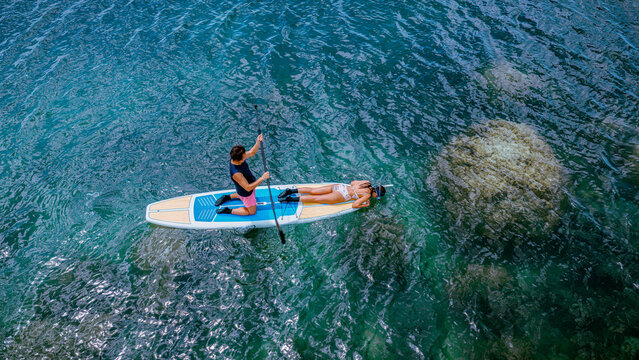 Top aerial view of Group of tourist are enjoy on water sport paddle sup-board  along at the sea under crystal clear of water in the island of summer trip