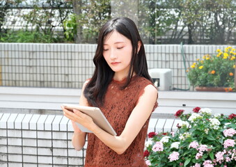 タブレット端末を持ち画面を操作する若い女性 © taka