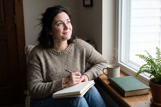 Reflective journaling by window with coffee in a cozy home moment