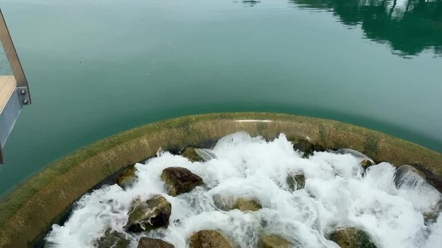 Scenic 4K horizontal footage Of Small Dam Waterfall &mdash; Clear Blue Water and Peaceful Nature, water flowing over a small rocky dam, surrounded by calm blue water and natural stones