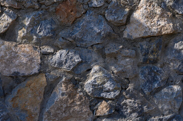 Fototapeta premium Textured stone wall showcasing a rich mix of colors and shapes under natural light in a rustic setting