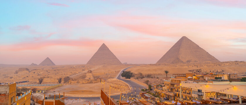 Panoramic view of ancient pyramids rising above a desert landscape at sunset in Cairo