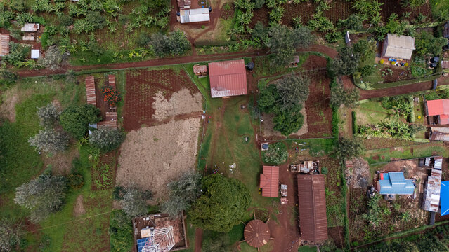 Aerial view of rural landscape featuring small farm plots, scattered houses with metal roofs, lush green vegetation, and dirt paths in the countryside in Gatundu, Kiambu County, Kenya.
