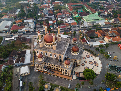 Aerial view of Al Aqsha Great Mosque with its prominent domes and minarets, surrounded by the dense urban landscape of rooftops and streets in Klaten, Central Java, Indonesia.