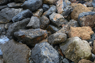 Rocky coastline reveals textured stones and pebbles under soft sunset light by the shore © Михаил Шорохов