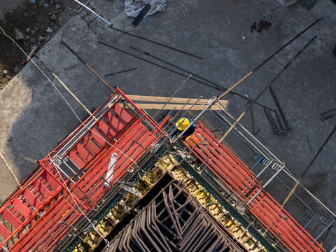 Aerial view of the construction of the Solo-Yogyakarta Toll Road with red scaffolding and steel rebar reinforcement at a site in Kecamatan Depok, Daerah Istimewa Yogya, Indonesia.