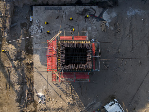 Aerial view of the Solo-Yogyakarta Toll Road construction site with a square concrete pillar formwork, scaffolding, and workers, Kecamatan Depok, Daerah Istimewa Yogya, Indonesia.