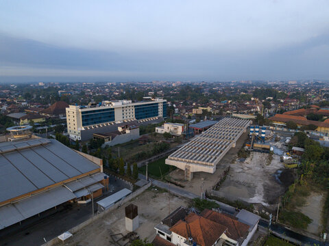 Aerial view of the Solo-Yogyakarta Toll Road construction site with concrete bridge segments and urban surroundings in Kecamatan Depok, Daerah Istimewa Yogya, Indonesia.