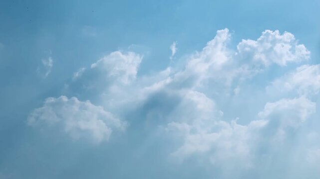 A 4K time-lapse captures sunlight filtering through moving clouds across a vivid blue sky. The changing natural atmosphere creates an uplifting visual for climate, travel, nature and cinematic project
