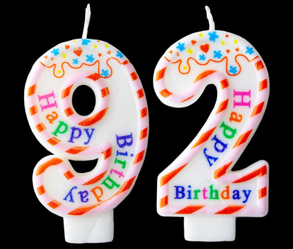Number ninety-two shaped birthday candle with colorful sprinkles and Happy Birthday text isolated on a black background