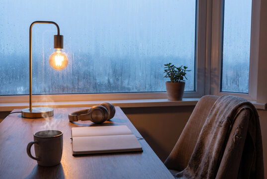 Cozy workspace by a rainy window with warm lamp light