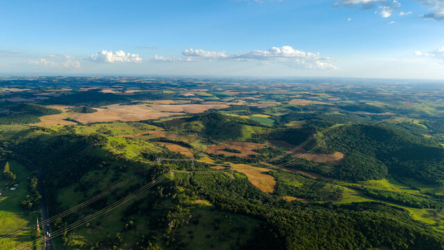 Aerial view of the BR-277 highway winding through the lush green hills and agricultural landscape of Laranjeiras do Sul, Parana, Brazil.
