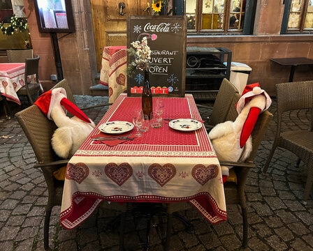 Christmas table with chairs decorated with stork-shaped toys on the city street. Strasbourg. France.