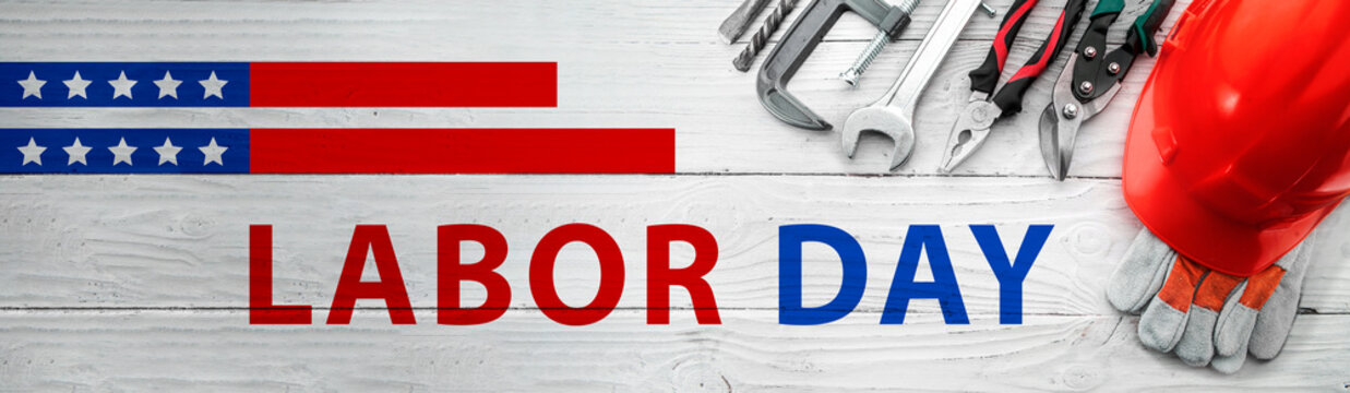 Labor Day greeting banner with construction tools on a white wooden background.