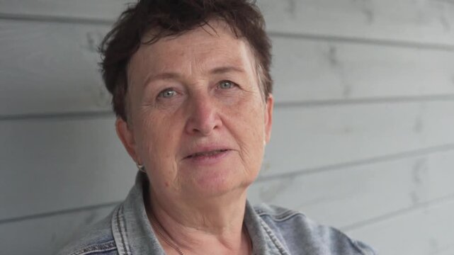 Close-up portrait of a happy mature woman, around 65 years old, looking at the camera with a calm and satisfied expression. Natural beauty, positive aging and relaxed lifestyle concept
