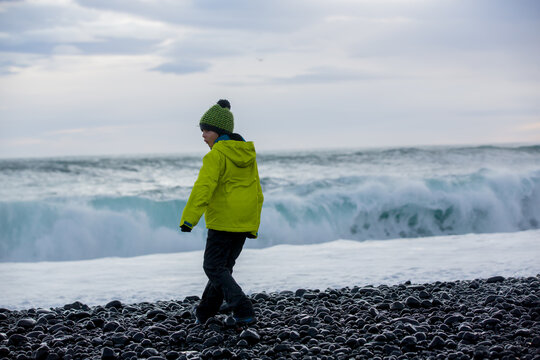 Child, playing on a beautiful beach in Snaefellsjokull National Park in Iceland, autumntime on sunset