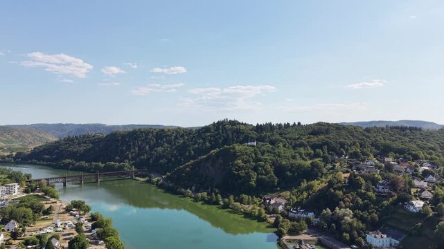 Aerial drone panorama of Bullay on the Moselle River in Rhineland-Palatinate, Germany, showing the river bend, riverside village, bridge and forested hills of the scenic Moselle Valley.