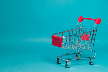 An empty small red metal shopping cart isolated on a vivid blue studio background with copy space. High Quality Photo © 7TridentSea