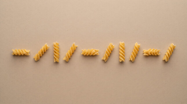 Golden Twisted Fusilli Pasta Spirals Arranged Creatively on Minimal Beige Background