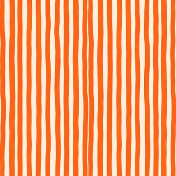 Seamless background pattern of hand drawn vertical wavy orange stripes on a light cream surface