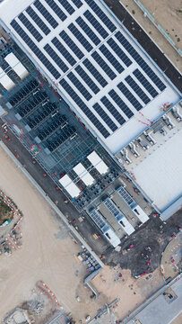 Aerial view of the BYES MIL08 data center featuring extensive rooftop solar panels and industrial cooling units in a construction setting in Siziano, Lombardia, Italy.