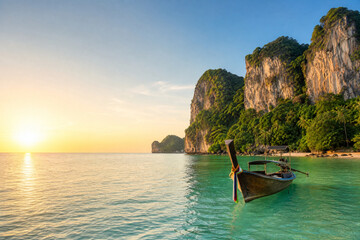 Obraz premium Traditional Long Tail Boat on Tropical Thai Coast at Sunrise