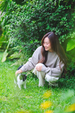 Vertical portrait of a woman playing with a black and white colors cat in the garden