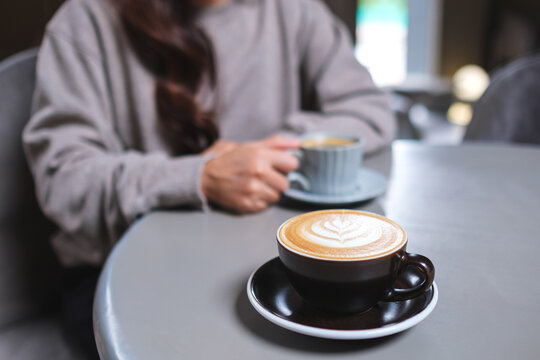 Closeup image of a woman holding and drinking coffee with friend