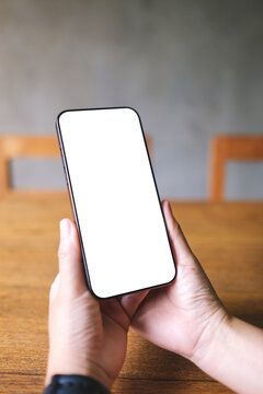 Vertical mockup image of a woman holding mobile phone with blank desktop screen