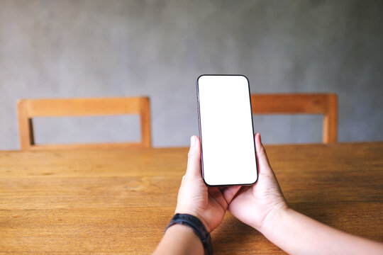 Mockup image of a woman holding mobile phone with blank desktop screen
